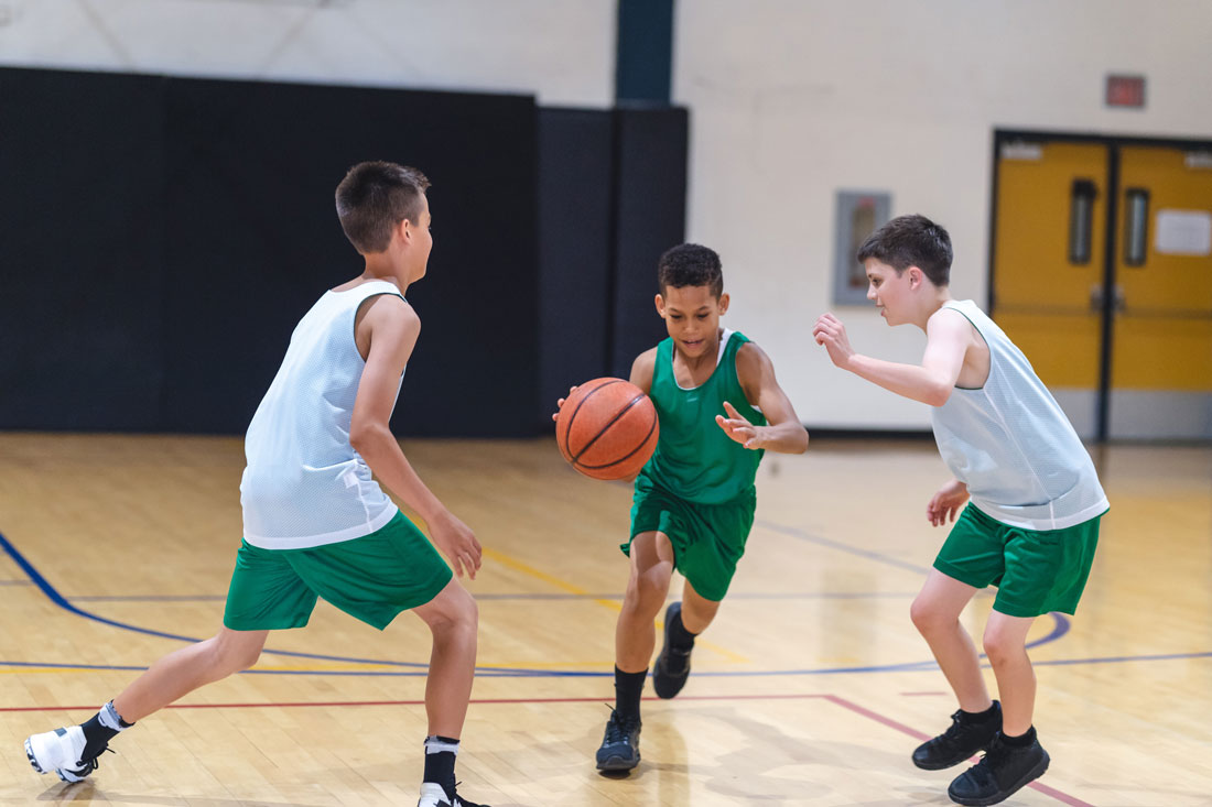 Boys playing basketball together in a school gym